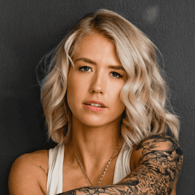 woman in gray tank top and black and white floral pants sitting on black floor