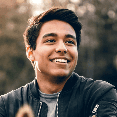 smiling man standing near green trees