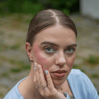 A woman gazes at the camera with her hand on cheek.