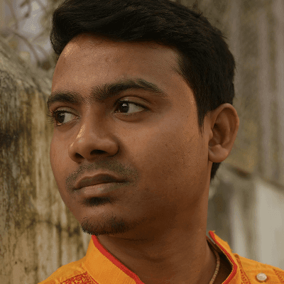 A man in a yellow shirt standing next to a tree