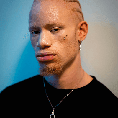 Man with braided hair and beard wearing necklace