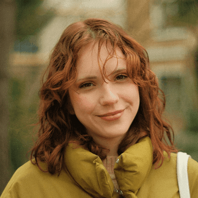 A woman with red hair is standing in the park