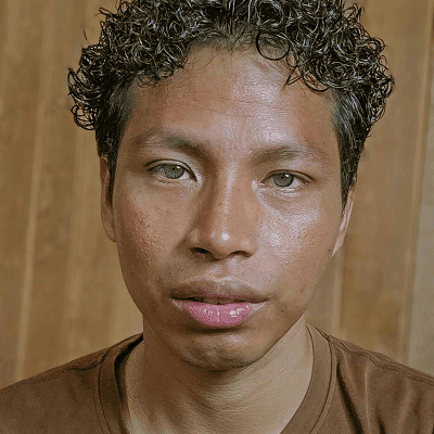 A man with curly hair looks directly at the camera.