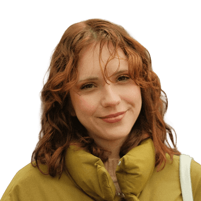 A woman with red hair is standing in the park